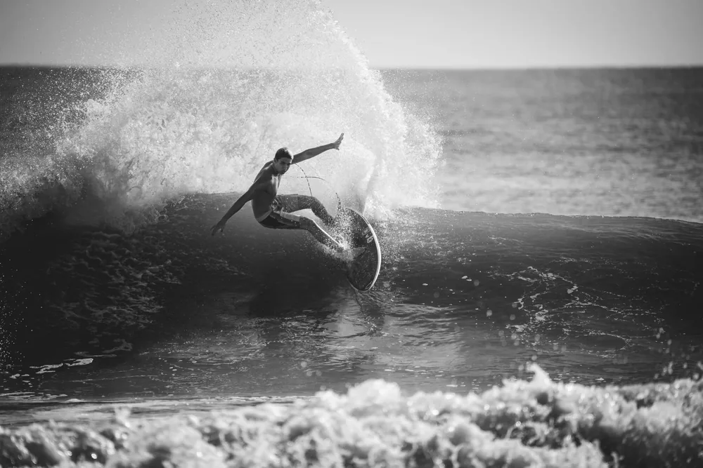 A surfer carving through the top of a wave
